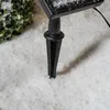 A close-up view of a black solar panel stake inserted into artificial snow, with a hint of green foliage in the background. Voir les images du produit