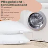 Two white pillows are stacked in front of a washing machine, with care instructions listed on the left. Produktbild-Vorschau