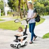 A woman pushing a child in a ride-on car with a stroller handle in a park. Produktbild-Vorschau