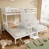 A white wooden bunk bed with stairs and storage, set up in a child's bedroom with bedding and toys. Náhled obrázku produktu