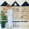 A young boy stands in front of a fabric advent calendar with 24 pockets, decorated with Christmas ornaments. Podgląd zdjęcia produktu