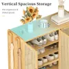 A close-up view of a wooden shoe cabinet with multiple shelves and doors, showcasing its storage capacity and design. Decorative elements like sunflowers and a vase are placed on top. Podgląd zdjęcia produktu