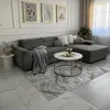 A living room scene featuring a sectional sofa, coffee table, and rug. Produktbild-Vorschau
