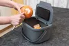 A person is peeling an orange over a compost bin. Anteprima dell’immagine prodotto