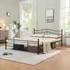 A bedroom scene with a metal bed frame, mattress, pillows, and a blanket. Voir les images du produit