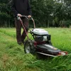 A person is using a rotary mower in a grassy field. Produktbild-Vorschau
