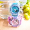Two G-Shock watches are stacked on top of each other, with a glass of water and grapes in the background. Produktbild-Vorschau