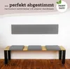 A bench with grey seat cushions and a grey headboard mounted on a white wall, with a wooden floor. Produktbild-Vorschau