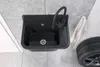 A black granite composite sink with a black faucet is shown in a utility room setting, next to a car tire and a white towel. Náhled obrázku produktu