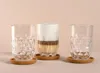 Three glasses on coasters, one filled with a layered coffee drink. Anteprima dell’immagine prodotto