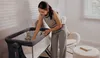 A woman is tending to a baby crib in a nursery. Produktbild-Vorschau