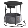 A round end table with a black top, a gray fabric basket, integrated power outlets and USB ports, and a power cord. Produktbild-Vorschau