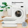 A washing machine and three pillows are shown in a clean, bright setting, with a plant in a pot on a stool. Produktbild-Vorschau