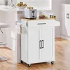 A white kitchen cart with a wooden top is shown in a kitchen setting next to a counter and a stool. Produktbild-Vorschau