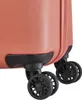 Close-up view of the wheels and bottom corner of a coral-colored suitcase. Produktbild-Vorschau