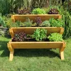 A tiered wooden planter filled with various herbs and leafy greens, set in a garden. Produktbild-Vorschau