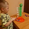 A young boy is playing with a colorful caterpillar-themed stacking game on a wooden table. Náhľad obrázku produktu