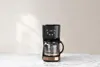 A black and copper coffee maker is displayed on a marble countertop against a light gray wall. Náhled obrázku produktu