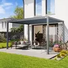 A modern pergola with a louvered roof is set up on a patio next to a house, furnished with outdoor seating and plants. Anteprima dell’immagine prodotto