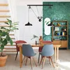 A dining area with a table, chairs, a plant, and shelving, decorated with green tiles. Anteprima dell’immagine prodotto
