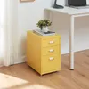 A yellow metal filing cabinet with three drawers sits next to a white desk. Náhled obrázku produktu