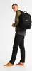 A man wearing a backpack and casual clothing, standing against a white background. Produktbild-Vorschau