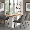 A dining table and chairs set in a well-lit room with a large window and a bookshelf. Voir les images du produit