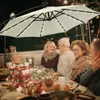 People enjoying a meal outdoors under a patio umbrella at night. Produktbild-Vorschau