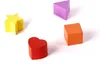 Four colorful wooden shapes (star, heart, cube, and triangle) arranged on a white background. Náhled obrázku produktu