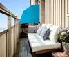 A balcony with a sofa, cushions, and a blue umbrella. Produktbild-Vorschau