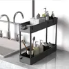 A two-tier black storage cart with various bathroom items on it, placed next to a sink. Produktbild-Vorschau