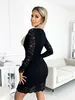 A woman wearing a black lace dress stands in a room with a sofa and a table. Náhled obrázku produktu