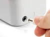 A hand is plugging a power adapter into a white electronic device. Voir les images du produit