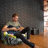 A man is sitting on a colorful bean bag chair and playing an electric guitar. Voir les images du produit