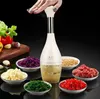 A hand is pressing down on a manual food chopper, surrounded by bowls of chopped ingredients. Náhľad obrázku produktu