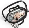 An overhead view of a black diaper bag filled with various baby items and a stuffed animal. Produktbild-Vorschau