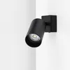 A black spotlight mounted on a white wall corner. Produktbild-Vorschau