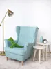 A plush dinosaur toy sits on a light blue armchair next to two small side tables, one with a vase and alarm clock, and a floor lamp is to the left. Anteprima dell’immagine prodotto