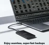 A black external SSD is connected to a laptop, with the laptop screen showing a grid of images. Produktbild-Vorschau