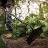 A person is using a Fiskars Solid Hacke in a garden. Produktbild-Vorschau