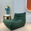 A green Togo-style armchair is placed in a minimalist room next to a statue on a small table. Voir les images du produit