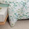 A close-up view of a bed with a duvet cover featuring a green and turquoise floral pattern. Produktbild-Vorschau