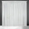 A white sheer curtain hanging against a dark gray wall. Produktbild-Vorschau