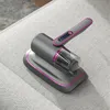 A handheld vacuum cleaner with a charging base is placed on a light gray fabric surface, possibly a sofa or mattress. Produktbild-Vorschau