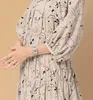 A close-up shot of a woman wearing a patterned dress and a silver watch. Produktbild-Vorschau