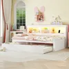 A child's bedroom with a white daybed, trundle bed, and a headboard with storage compartments and LED lighting. Podgląd zdjęcia produktu