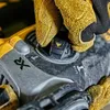A close-up shot of a person wearing yellow work gloves adjusting a dial on a power tool. Produktbild-Vorschau