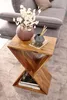A wooden side table with decorative items on top and books underneath, placed next to a sofa. Podgląd zdjęcia produktu