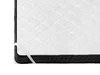 A close-up view of the corner of a white quilted mattress topper with black sides and elastic straps. Náhled obrázku produktu