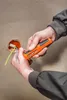 A person is using a wire stripper tool to strip wires near an electrical outlet. Produktbild-Vorschau
